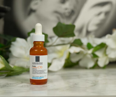 An unopened bottle of the La Roche Posay Pure Vitamin C10 Serum in front of flowers and a black and white photography.