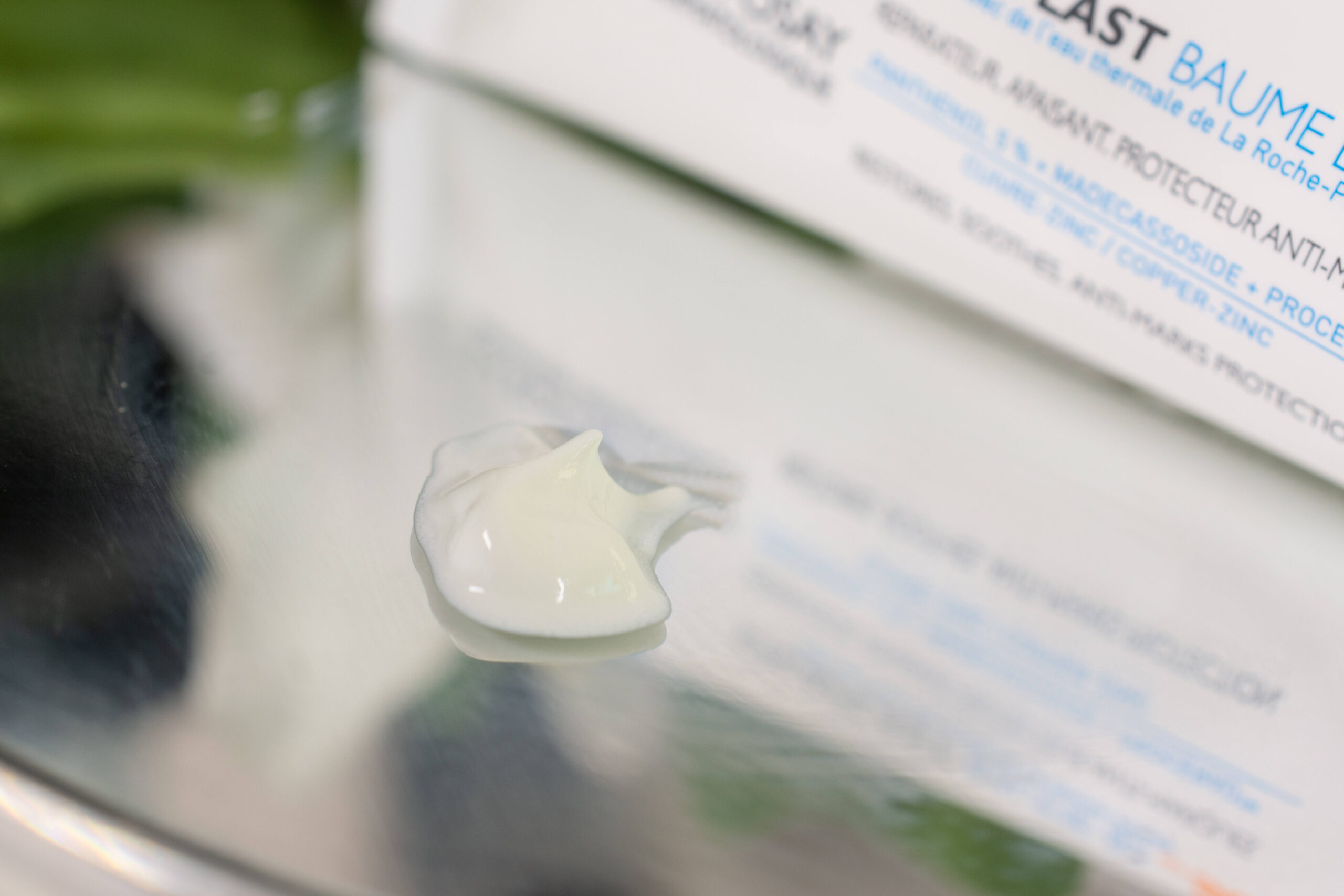 Close up of the La Roche Posay Cicaplast Baume B5 SPF 50, a thick, off-white cream on a mirrored surface.