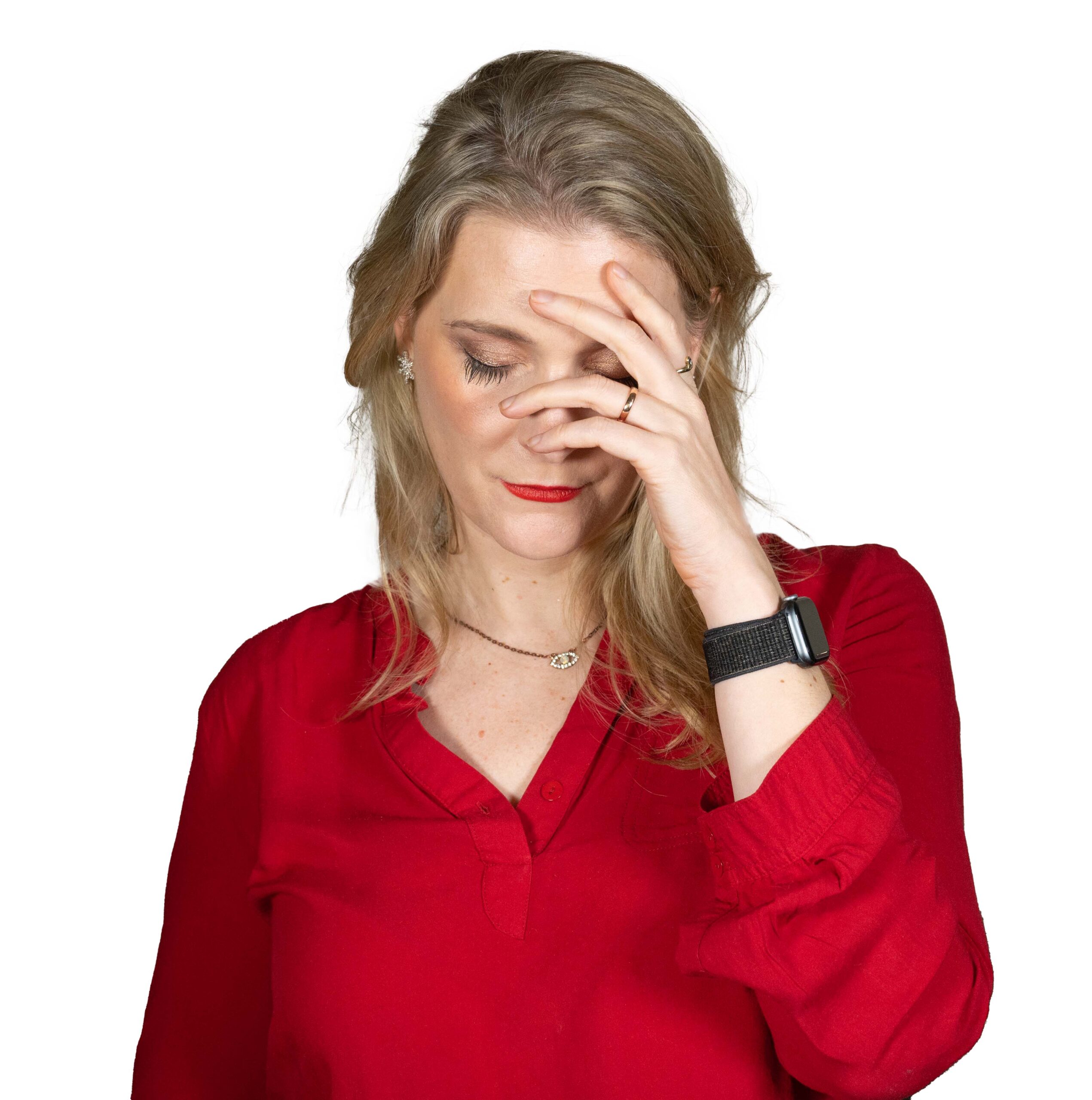 Blonde woman looking sad and covering half of her face with her hand