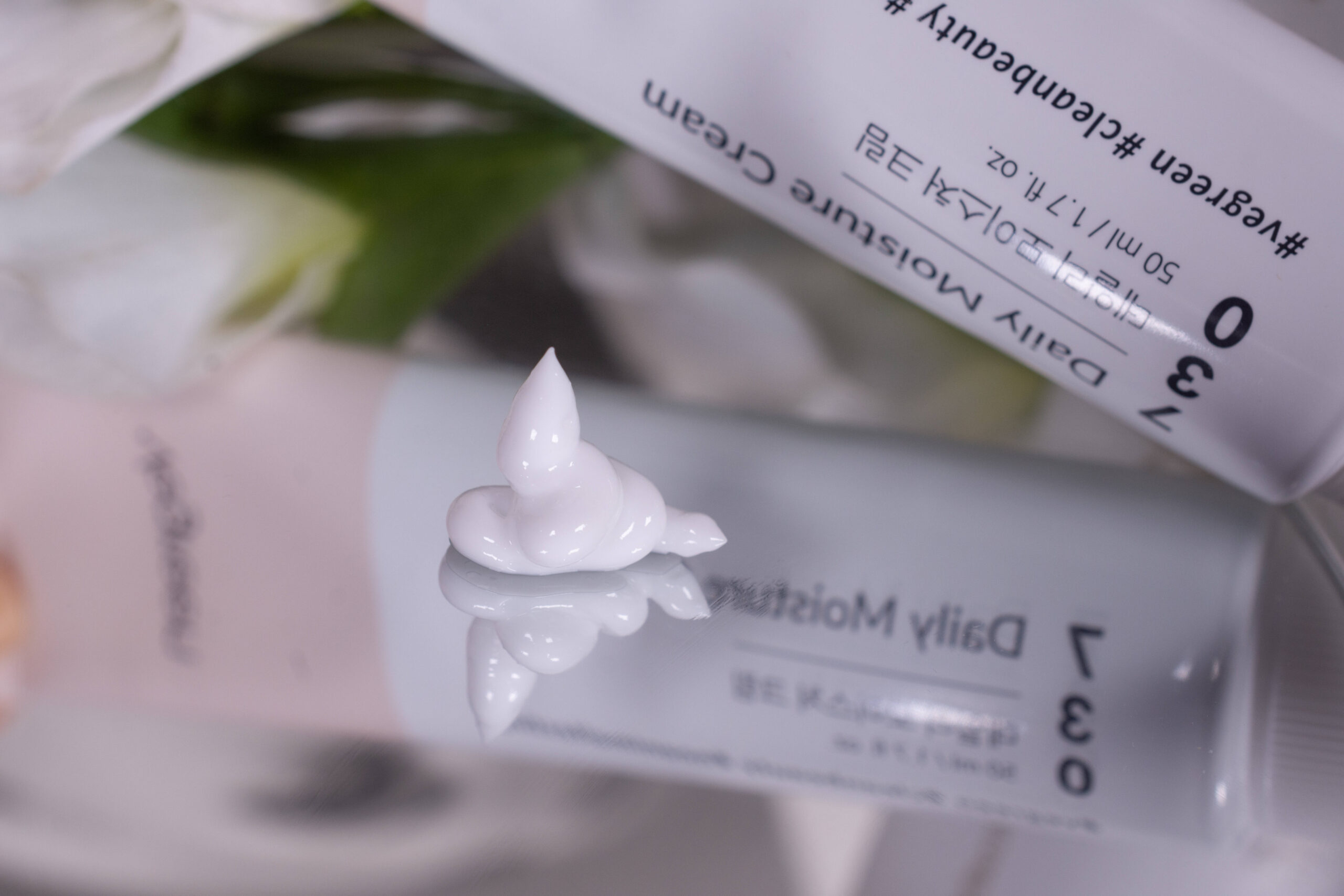 A close up of the Vegreen Daily Moisture Cream on a mirrored surface. It is a firm, white cream.