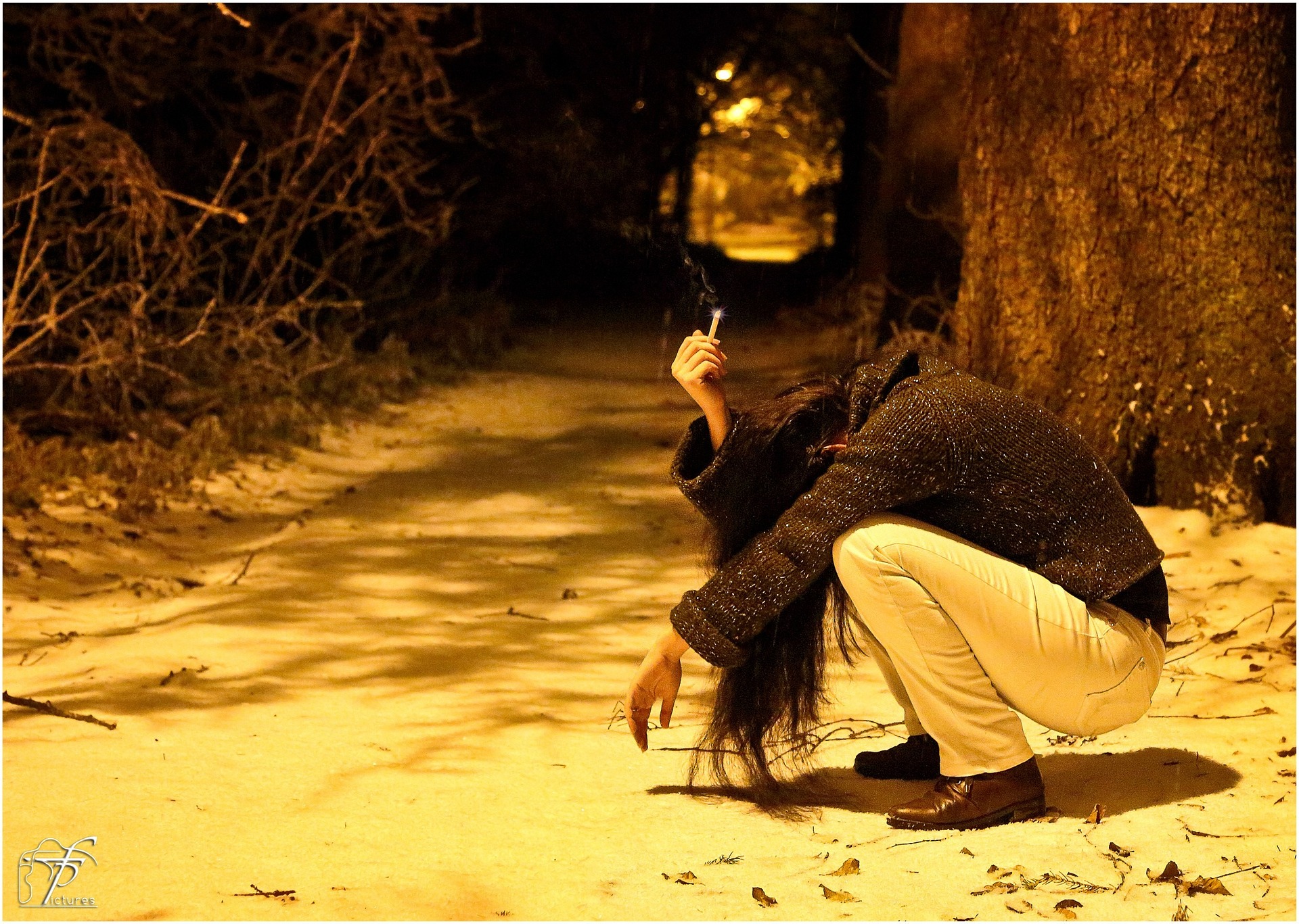 Young woman crouching in the snow, smoking