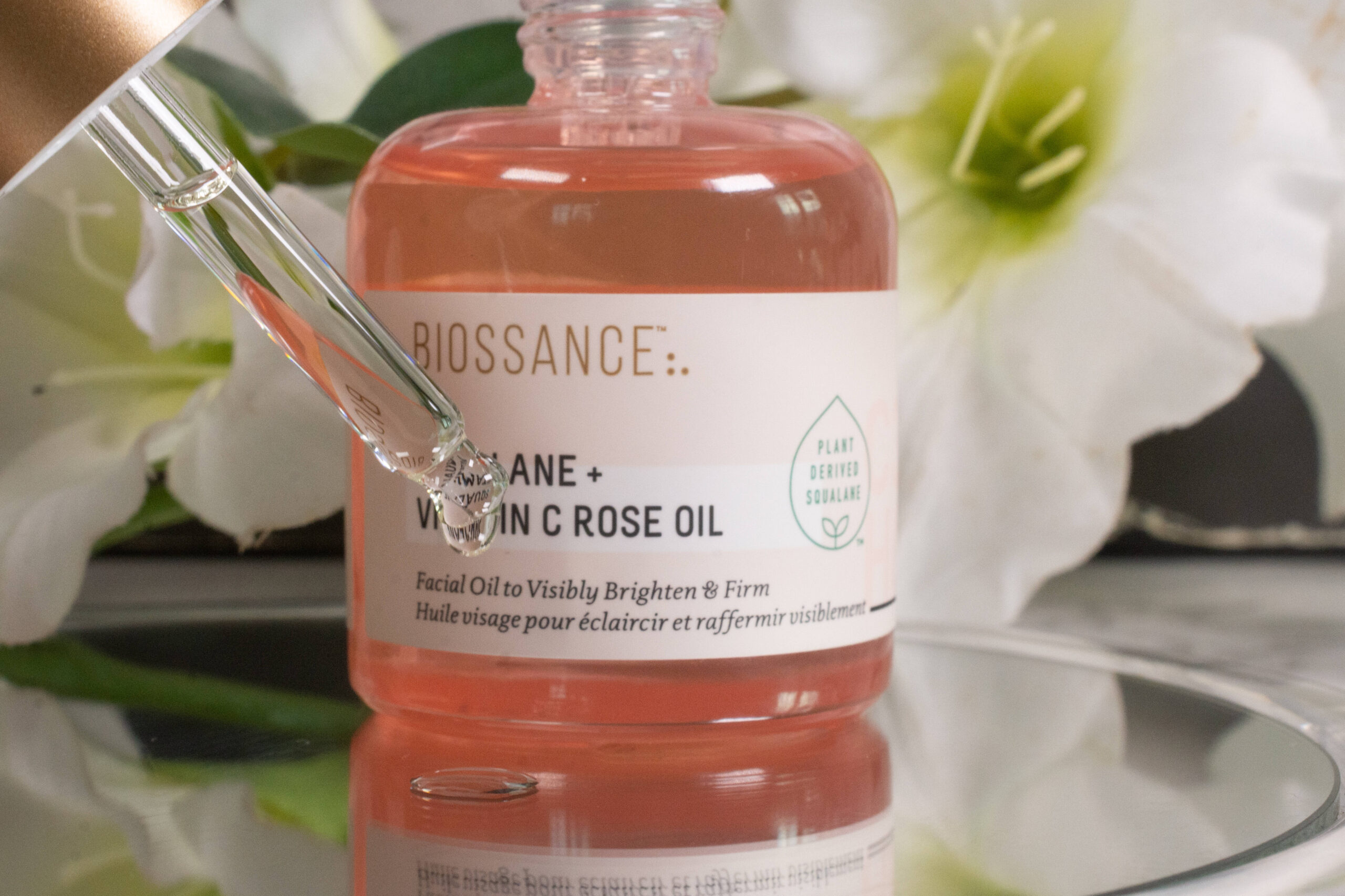 Close up of the Biossance Squalane and Vitamin C Rose Oil, a slightly yellow oil that does not have the same color as the rose-colored glass bottle.