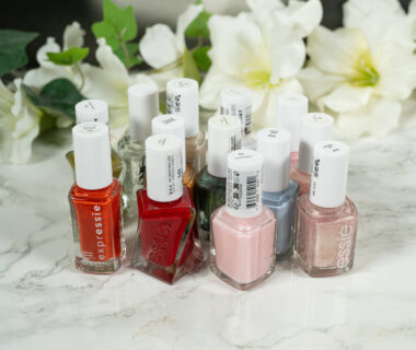 essie nail polishes standing in front of a dark background with white flowers