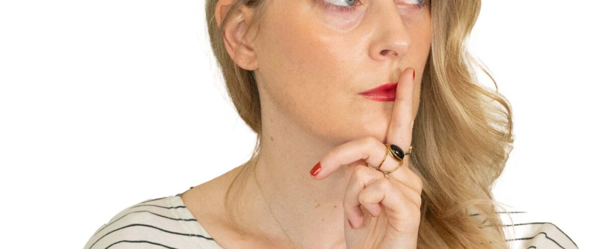 Blonde woman with a finger on her lips