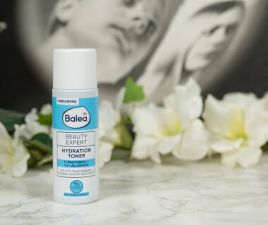 A bottle of Balea Beauty Expert Hydration Toner standing in front of a dark background with white flowers