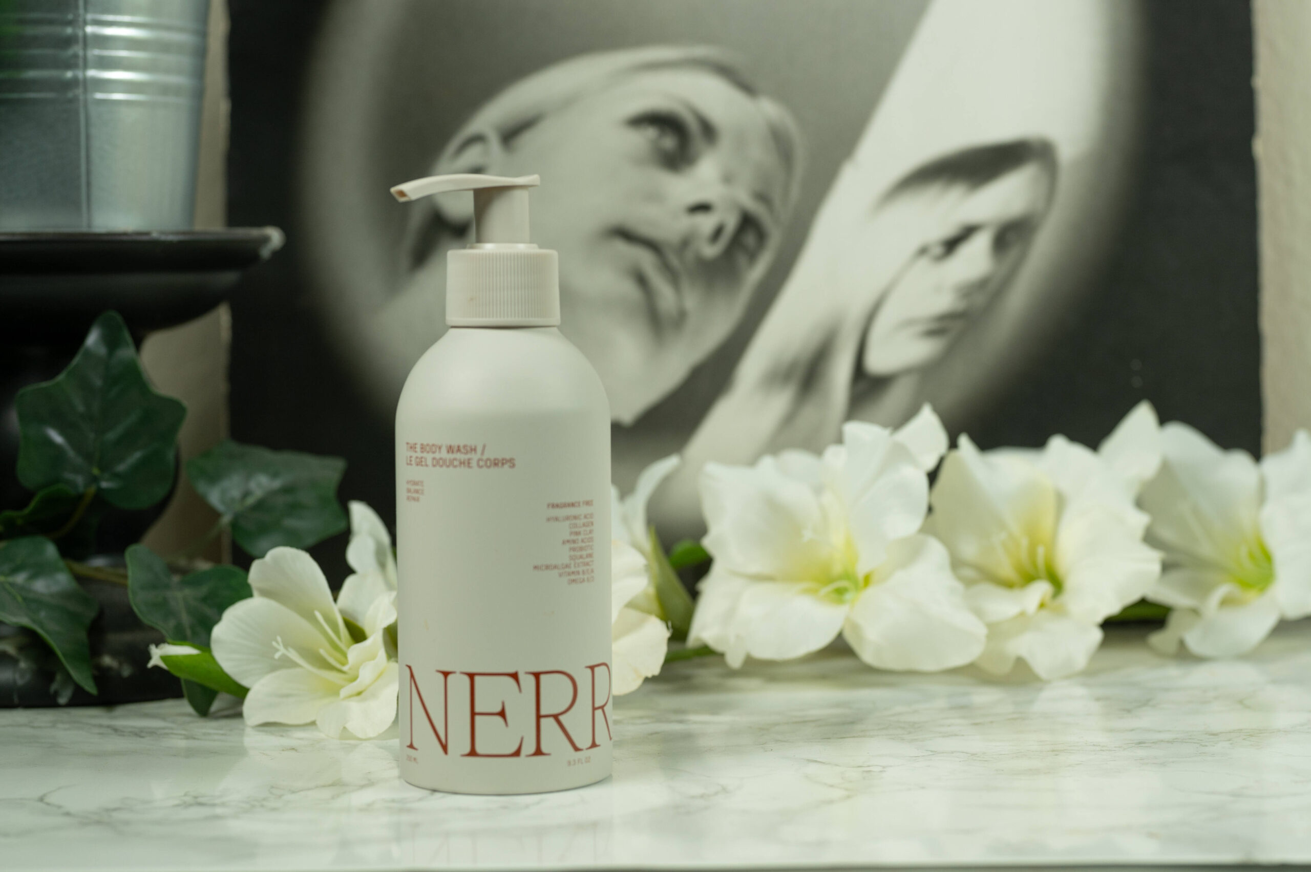 Nerra The Body Wash standing in front of a dark background with white flowers